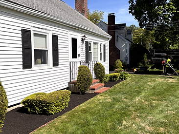 House front with fresh mulch, trimmed bushes and a crew working