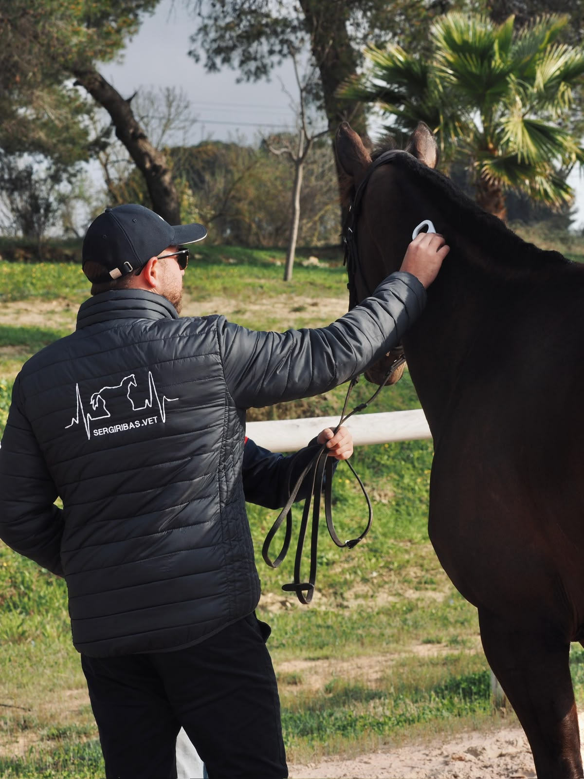 Sergi Ribas, veterinari equí, amb un cavall en un entorn eqüestre a l’aire lliure