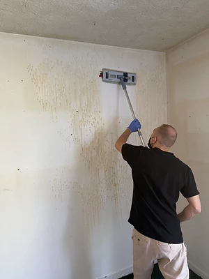 Membre de l’équipe nettoyant un mur avec un outil à manche.