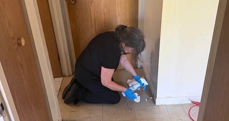 Membre de l’équipe à genoux nettoyant les plinthes dans un corridor.