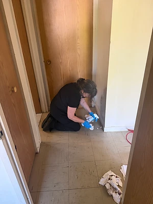Membre de l’équipe à genoux nettoyant les plinthes dans un corridor.