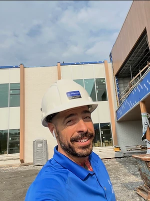 Membre de l’équipe portant un casque avec le logo de l’entreprise devant un chantier.