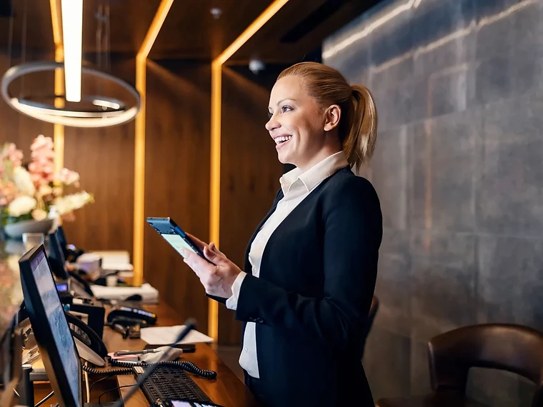 Hotel front desk team member using a tablet to support direct bookings