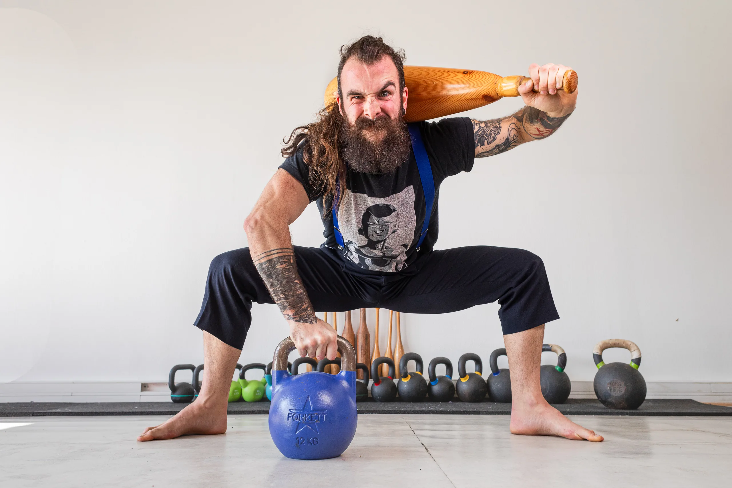 Athlète en squat avec macebell sur les épaules et kettlebell au sol