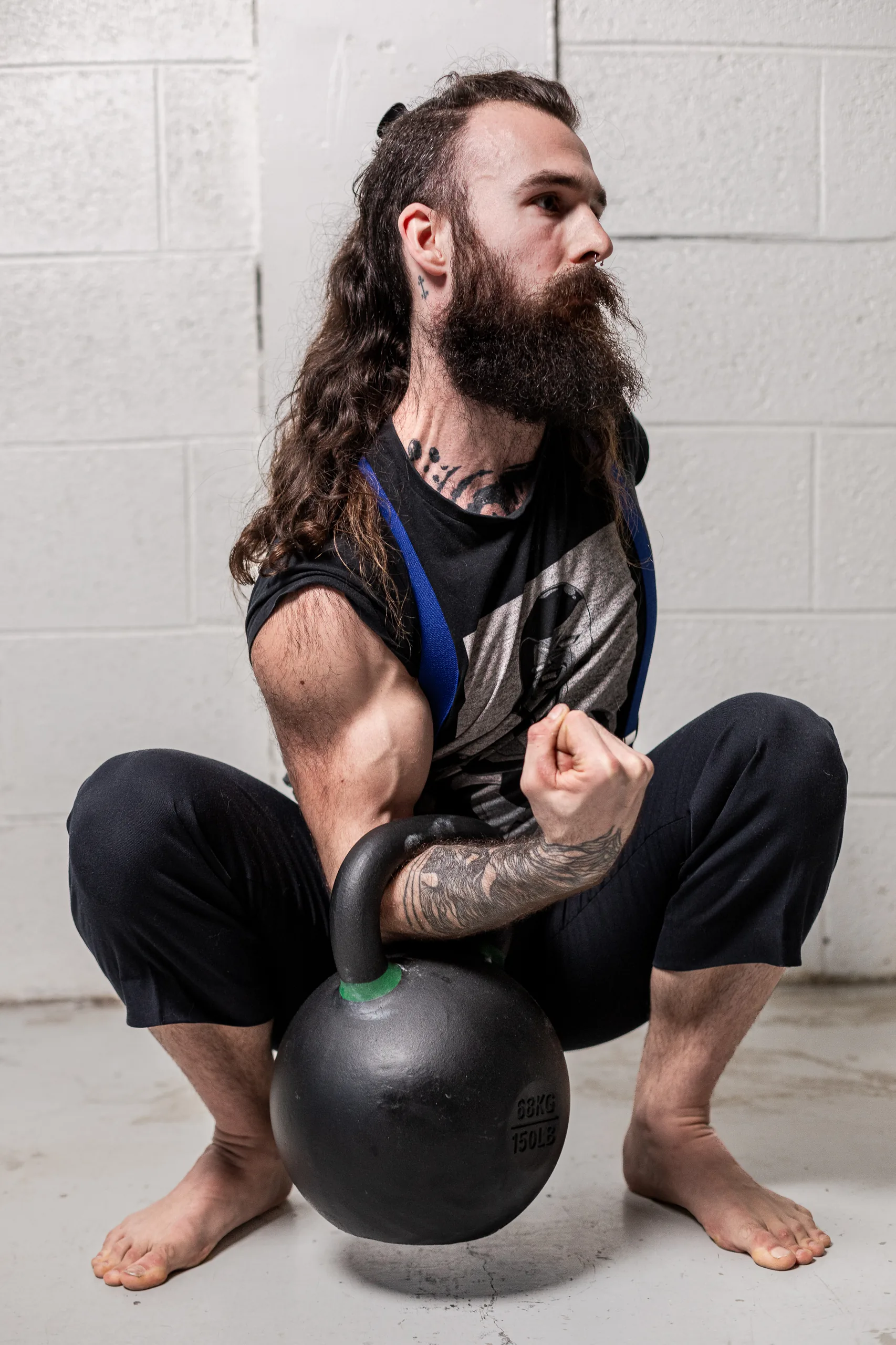 Athlète en squat profond avec une kettlebell au sol