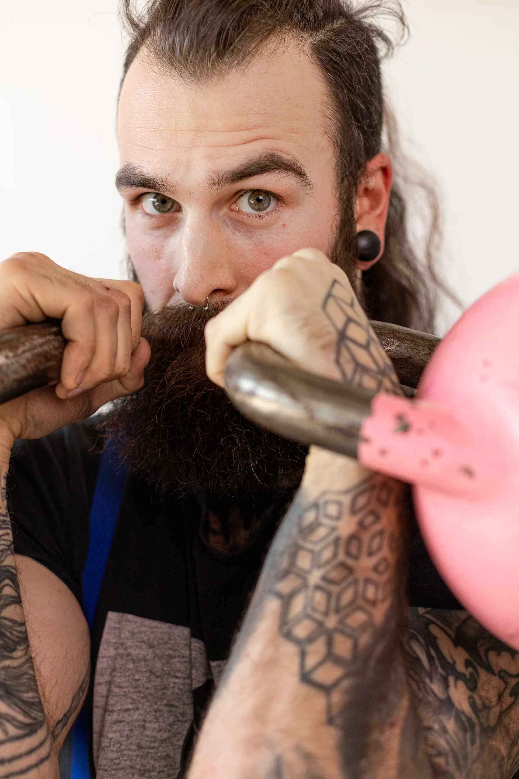 Portrait d'un athlète tenant une kettlebell rose près du visage