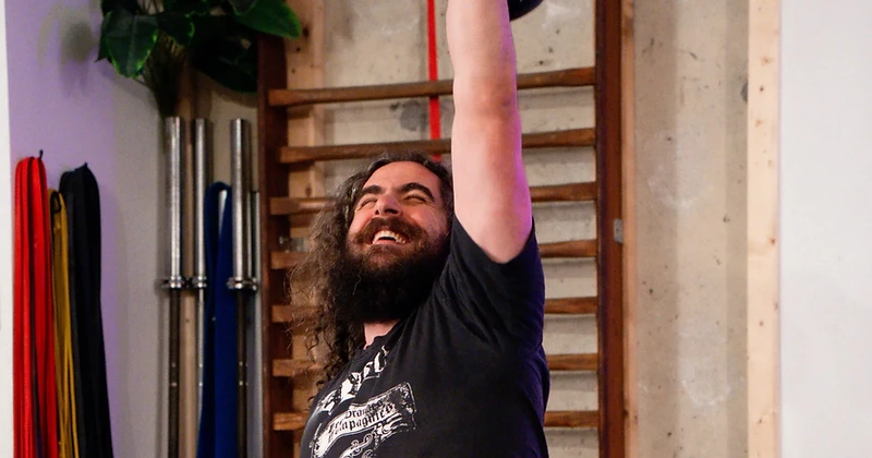 Coach The Roar Style souriant, développé kettlebell une main au-dessus de la tête