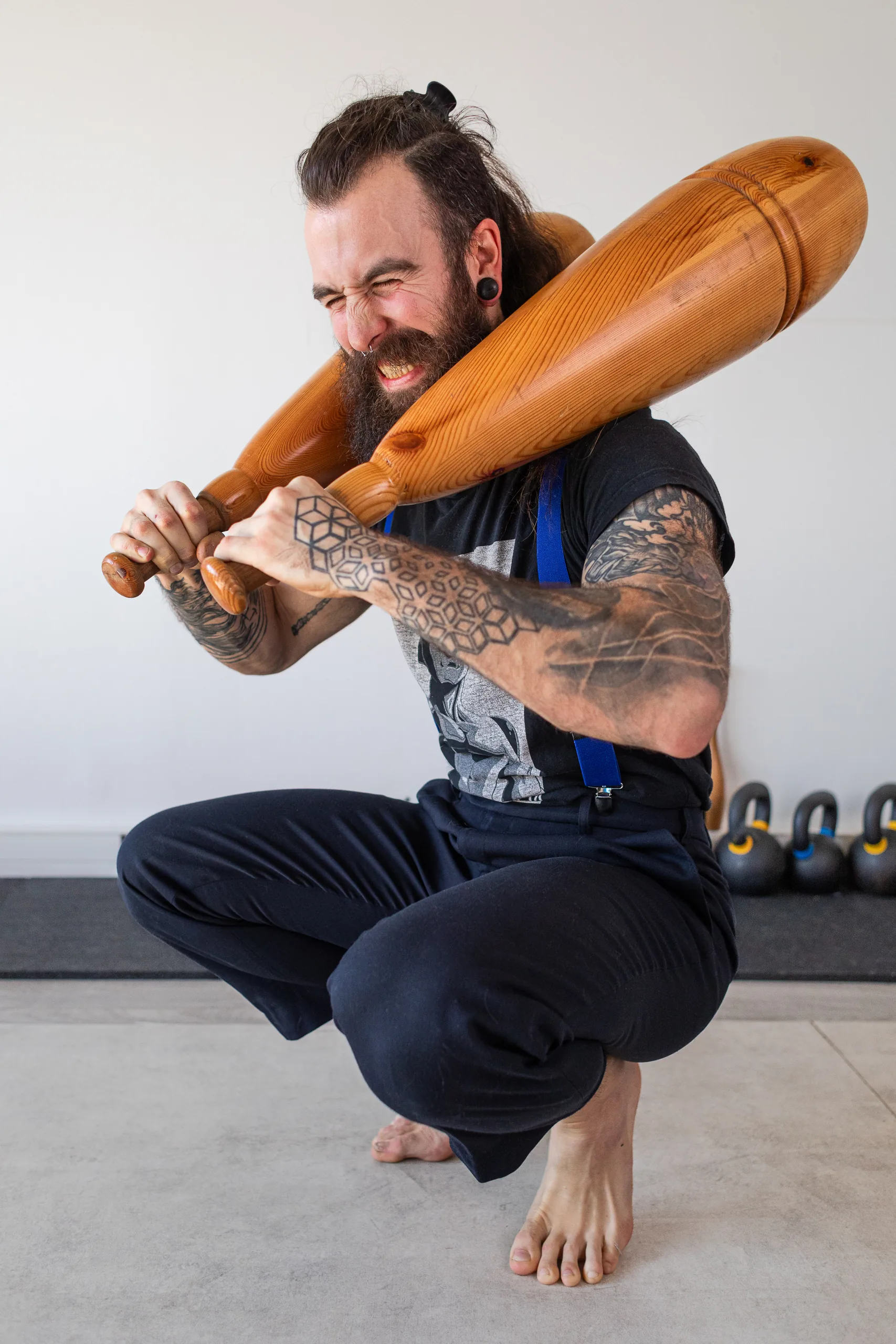Athlète en squat avec des massues en bois sur les épaules