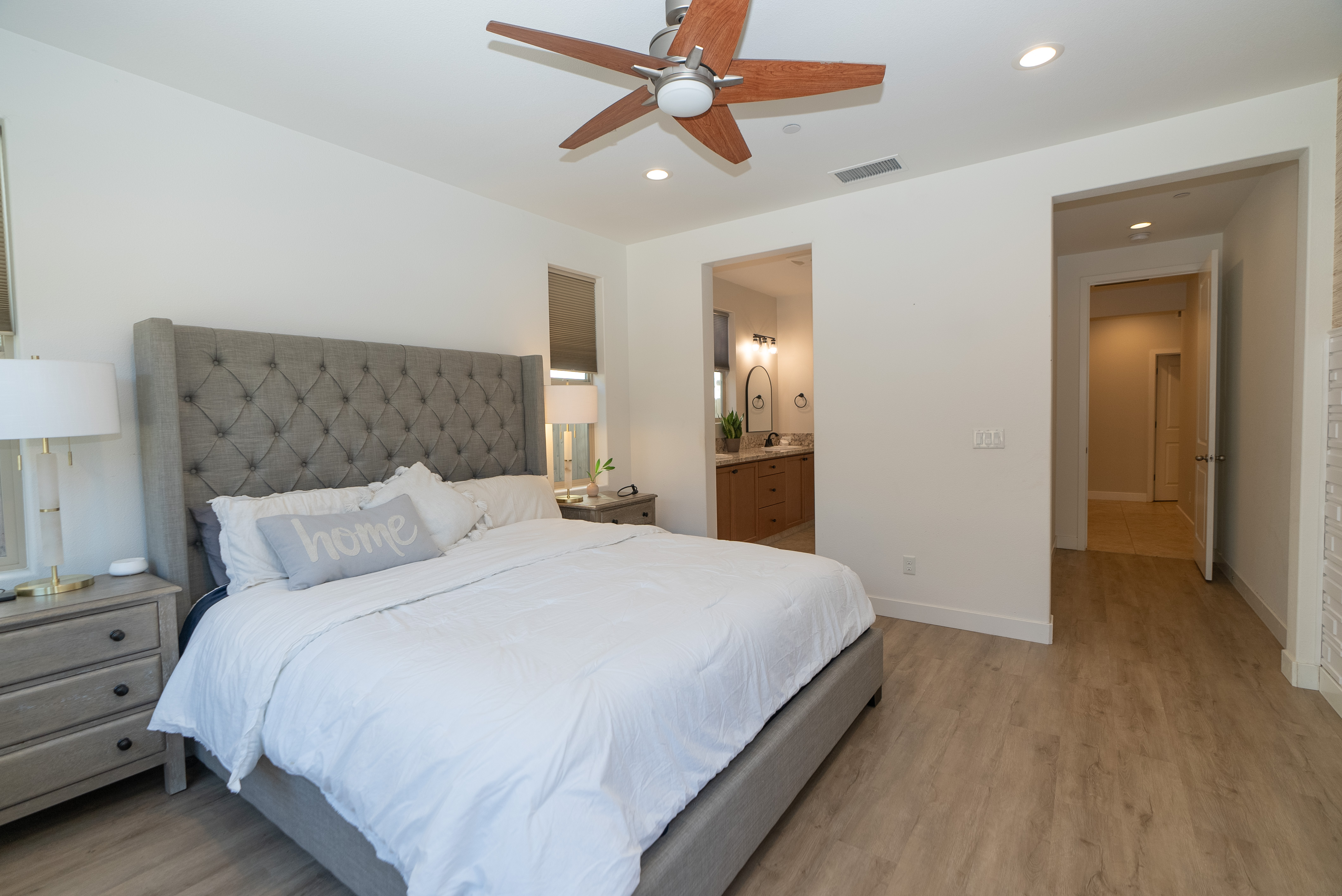 Serene primary bedroom with grey tufted headboard and warm wood flooring