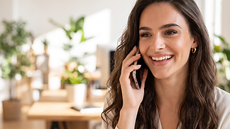 A receptionist smiling while taking a call on her phone in a bright office