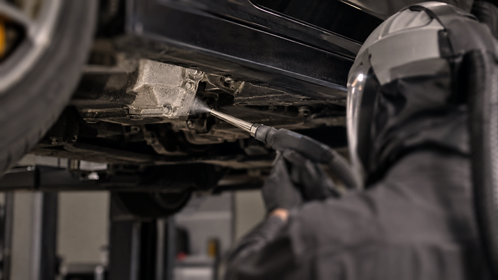 A technician dry ice cleaning a vehicle's undercarriage, the method at work.