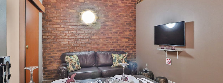 D Block lounge with flat-screen TV and dining counter at Rudman Townhouses