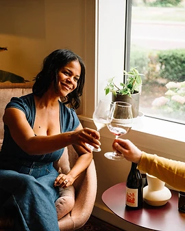 Michele Cary raising a glass of wine by the window