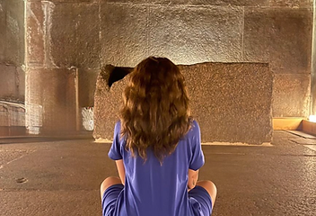 A figure seated in meditation before an ancient stone sarcophagus