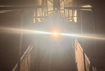 Narrow stone stairwell lit by a single point of light