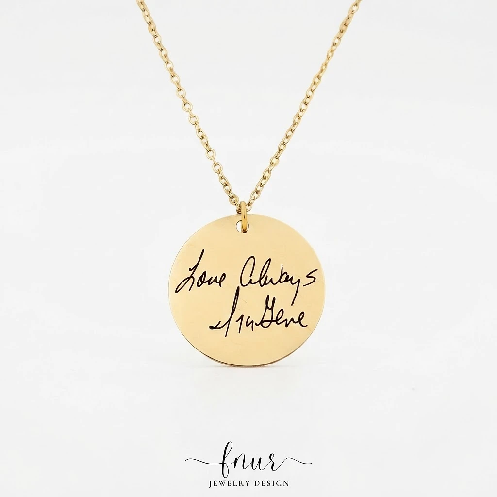 close up macro detail of authentic handwritten signature engraving on gold disc pendant