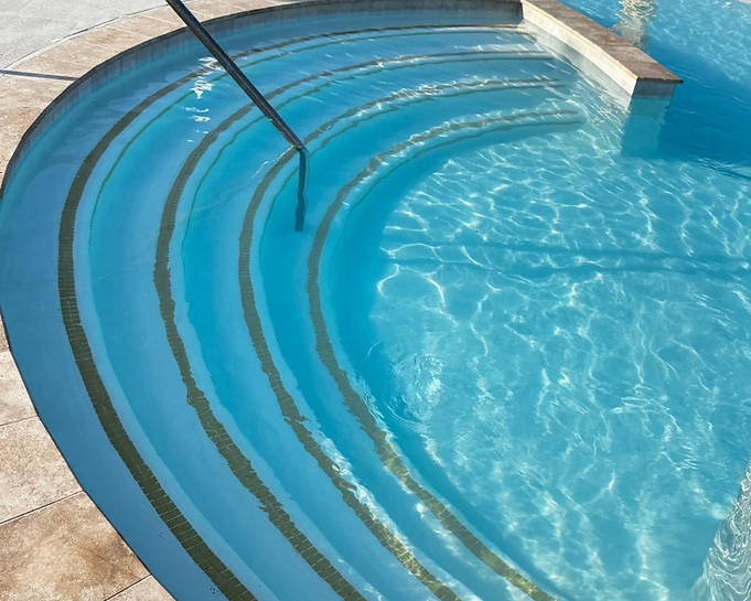 Curved pool entry steps beneath clear water