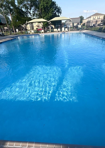 Blue swimming pool beside a paved deck and shaded seating
