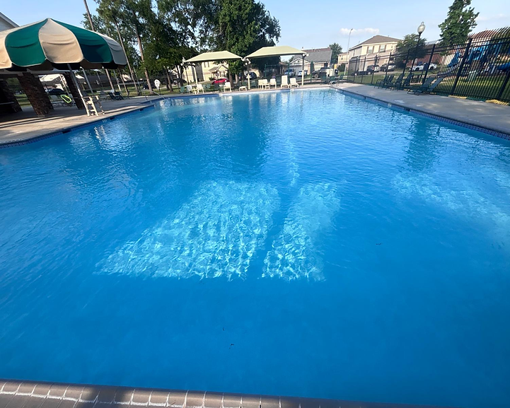 Blue swimming pool beside a paved deck and shaded seating