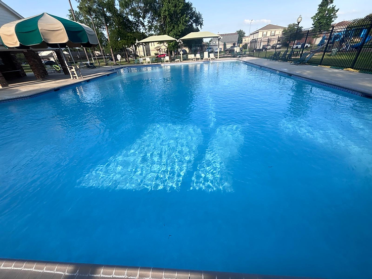 Blue swimming pool beside a paved deck and shaded seating