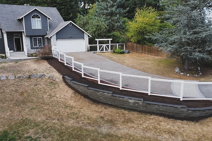 Tiered stone retaining wall with a white-framed wire fence