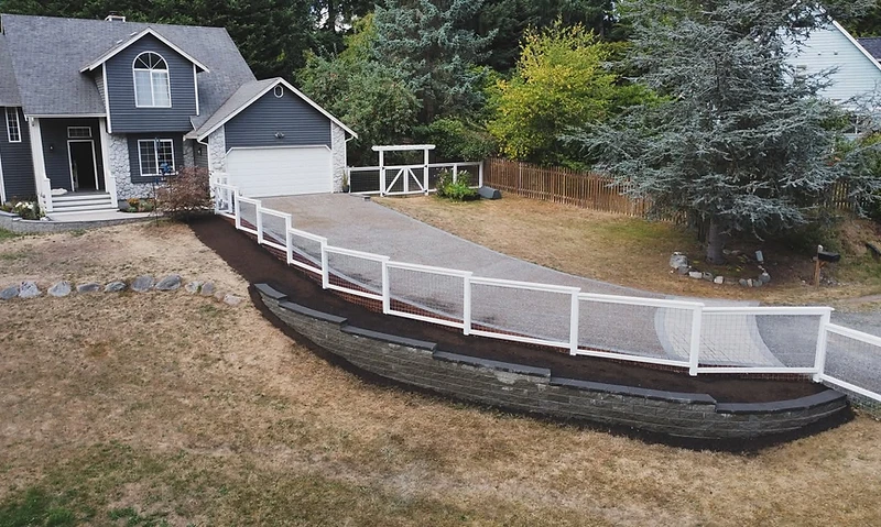 White-framed wire fence following a curved stone retaining wall — Elite Fencing & Landscaping
