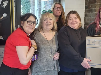 Impact Buckingham volunteers Hilary Whates and Jo Sadler, new landlady of The Mitre, with staff from George Grenville Academy and a hamper box