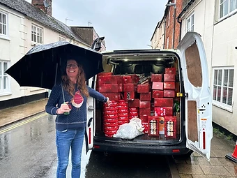 Impact Buckingham trustee Seonad McHugh beside a van packed with festive hamper boxes on a rainy Buckingham street