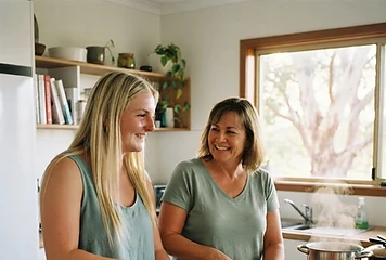 A support worker chopping vegetables with a smiling participant in a bright home kitchen