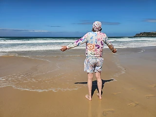 Arms wide, taking in the waves on a beach walk