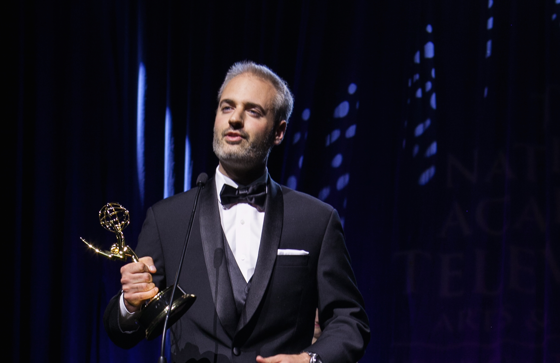 Nathan Pangrazio holding his Emmy Award in a black-and-white portrait