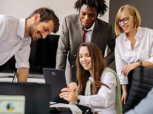 A diverse team collaborating around a tablet in a bright modern office.