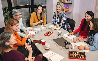 A group of professionals collaborating around a meeting table in a modern, naturally lit office.