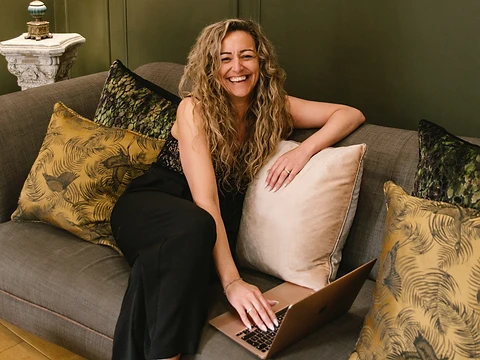 Terri Brown working on a laptop on a sofa.