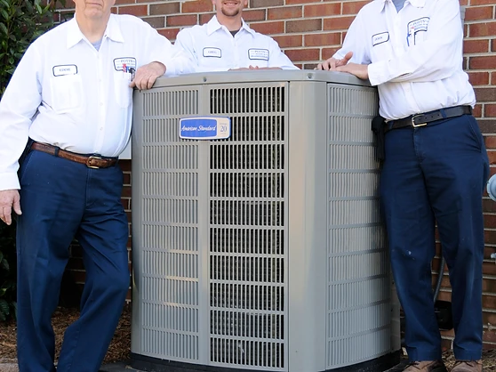 Three Potts' technicians behind an American Standard HVAC unit