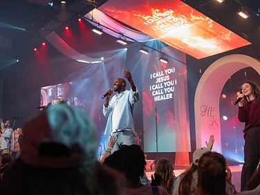 Vocalists leading worship beneath lyric screens