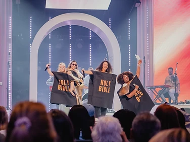 Performers in Holy Bible tunics on the conference stage