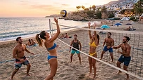 Grupo de amigos jugando al voley playa en una costa soleada de España