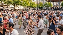 Grupo de personas sonriendo mientras bailan swing al aire libre en un parque