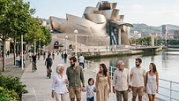 Grupo de personas paseando alegremente por la orilla de la ría de Bilbao frente al Museo Guggenheim