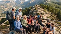 Grupo de senderistas diversos disfrutando de un descanso en una ruta de montaña en España