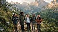 Grupo de personas haciendo senderismo en una montaña española con ropa de deporte sostenible y mochilas.
