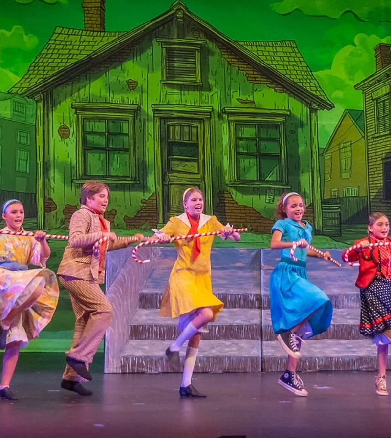 A Willy Wonka ensemble dancing with candy canes