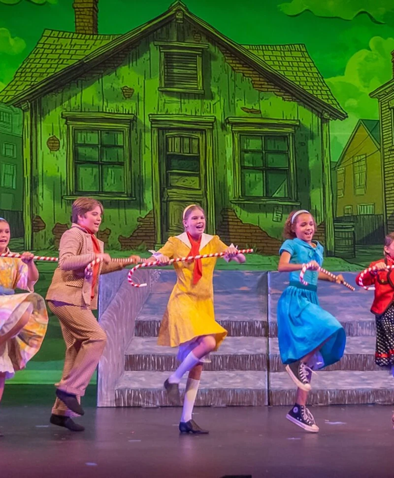 A Willy Wonka ensemble dancing with candy canes