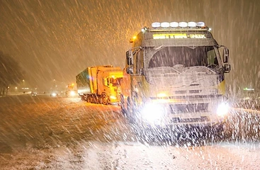 Bergingswagen aan het werk tijdens een sneeuwstorm in het donker