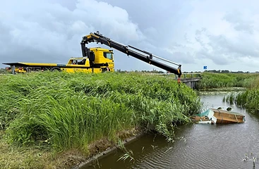 De bergingskraan van Betten Sneek boven het water bij een berging aan de waterkant