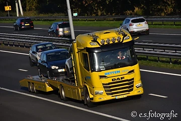 De gele autotransporter van Betten Sneek met een auto op de lading op de snelweg