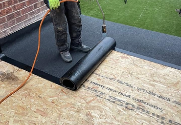 Roofer torching on bitumen felt over an OSB deck