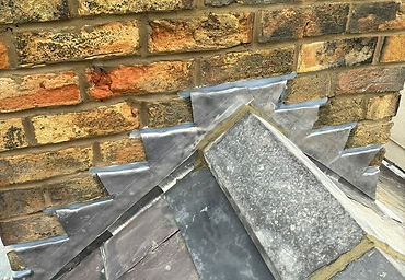 Stepped lead flashing along a slate verge against a chimney