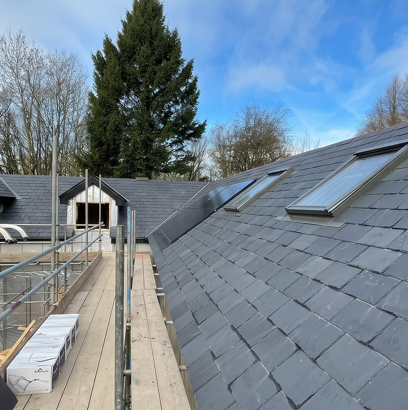 New slate roof with skylights beside scaffolding